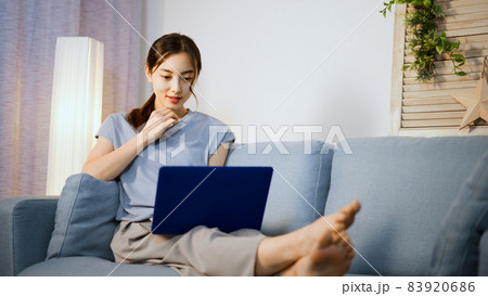 ソファーでノートパソコンを使う若い女性 83920686