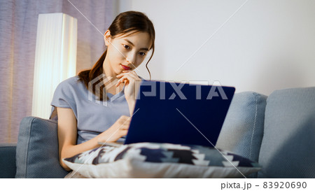 ソファーでノートパソコンを使う若い女性 83920690