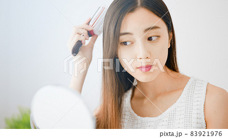 髪にブラシをかける若い女性 83921976
