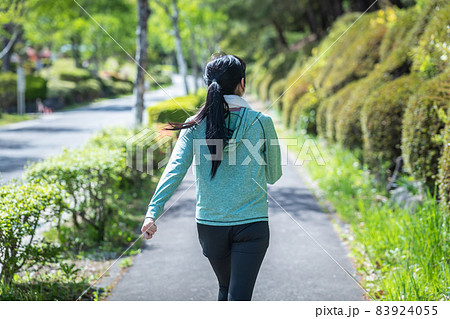 緑の中でウォーキングする女性（後ろ姿・タオル）の写真素材 [83924055