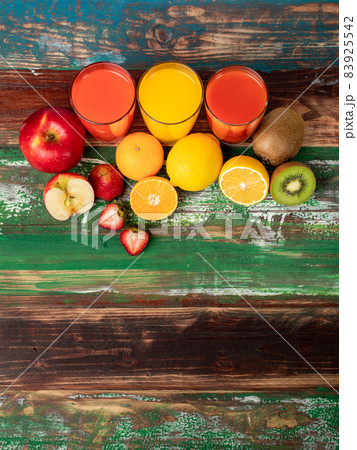 Different fruits juice in glass, apple, orange and strawberry juice, looking refreshing on colourful wood board. Picture decorating with fresh fruits 83925542
