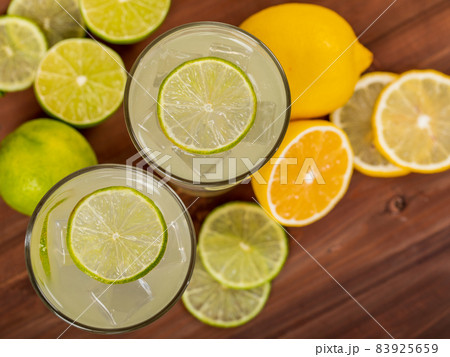 A close up picture of refreshing glasses of cold fruit juice, ice lime and lemon juice, decorating with fresh lime and lemon on wooden table. Concept for refreshing. 83925659