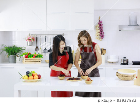 Happy ethnic housewives serving table with assorted tasty food for lunch in kitchen at home Happy ethnic housewives serving table with assorted tasty food for lunch in kitchen at home 83927832