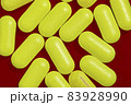 Yellow tablets capsules on dark red background. 83928990
