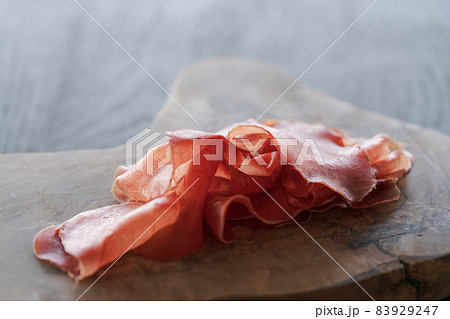 bresaola slices on olive wood board 83929247