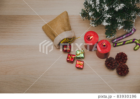 Top view studio shot of Christmas eve festival decorative items small sack bag full of gift present boxes Red candles Pine seeds Mock up xmas tree and Candy cane stick on wooden table with copy space Top view studio shot of Christmas eve festival decorative items small sack bag full of gift present boxes Red candles Pine seeds Mock up xmas tree and Candy cane stick on wooden table with copy space 83930196