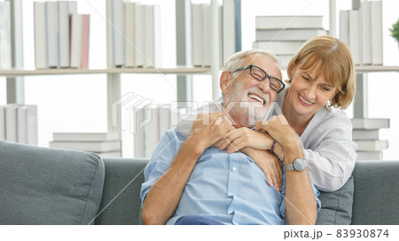 Caucasian old senior happy grandparents grey bearded hair husband and pretty wife sitting cuddling laughing together on sofa in living room at home watching comedy movie from laptop computer Caucasian old senior happy grandparents grey bearded hair husband and pretty wife sitting cuddling laughing together on sofa in living room at home watching comedy movie from laptop computer 83930874