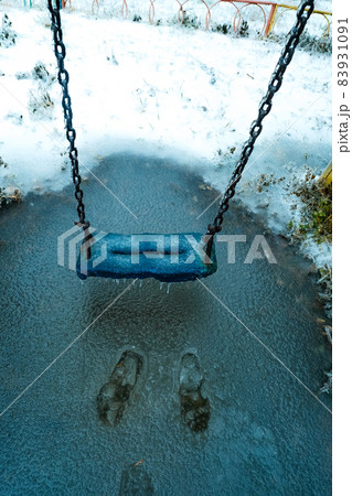Empty swing in the playground in the park, wooden swing, wooden swing in winter, icicles on the swing 83931091
