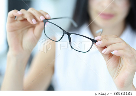 Woman holding glasses for vision, close-up Woman holding glasses for vision, close-up 83933135