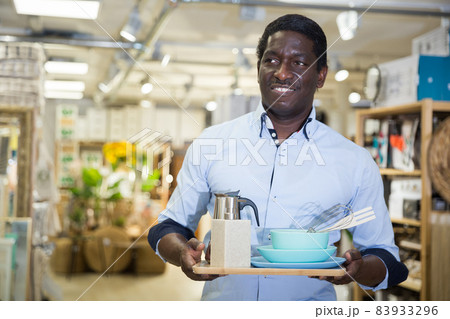 Smiling african american man with purchases in home furnishings store Smiling african american man with purchases in home furnishings store 83933296