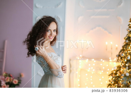 Leggy brunette in an elegant dress decorates a Christmas tree Leggy brunette in an elegant dress decorates a Christmas tree 83936306