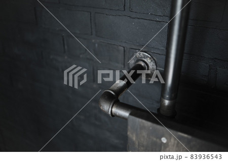 Black brick wall with installed pipe. Minimalistic background Black brick wall with installed pipe. Minimalistic background 83936543