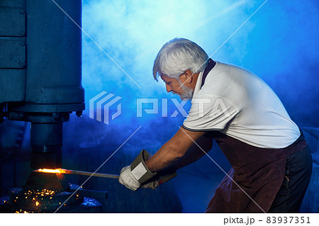 Blacksmith bending heated steel under press machine 83937351