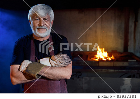 Caucasian blacksmith posing with crossed arms at forge Caucasian blacksmith posing with crossed arms at forge 83937381