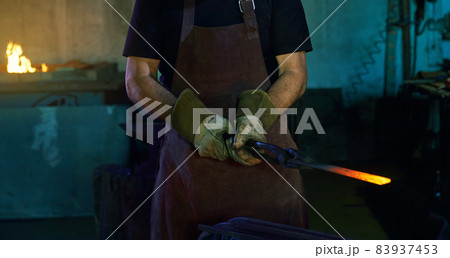 Close up of blacksmith holding pliers with hot steel 83937453