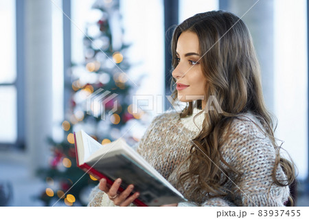 Woman reading book during winter holidays at home 83937455