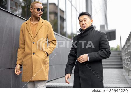 Businessmen walking on city street and talking 83942220