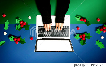 Person using a laptop computer with Christmas holly berries 83942877