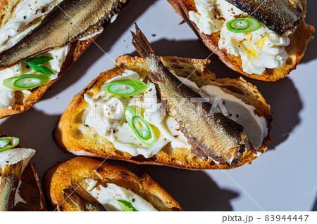 Toasts with cream cheese, fish sprats (sardine) and green onions, close-up. Simple homemade recipes concept. 83944447
