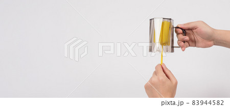 Clean and wash dish concept. Man hand washing drink glass on white background. Used drinking glass cleaning by soft yellow sponge stick. Wash cup by sponge brush. Disinfection hyginic in covid 19 era 83944582