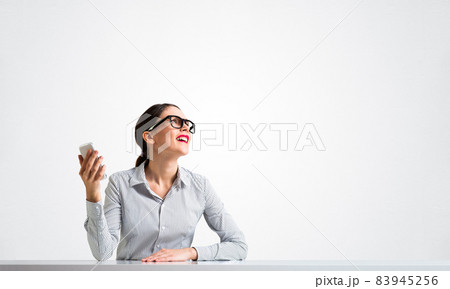 Smiling young woman sits at desk Smiling young woman sits at desk 83945256