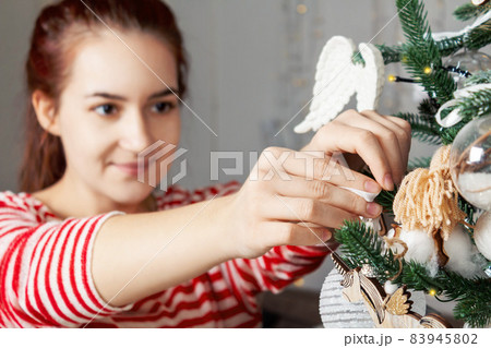 Young beautiful caucasian woman decorating Christmas tree. Young beautiful caucasian woman decorating Christmas tree. 83945802