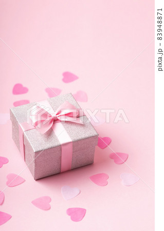 Silver glitter gift box with pink ribbon bow on pink background with confetti. 83948871