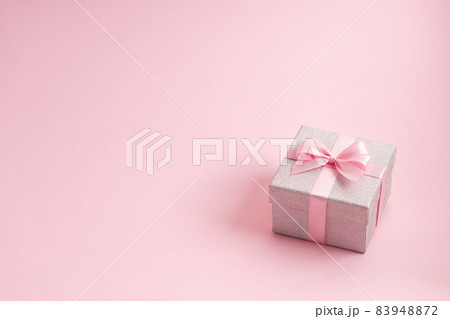 Silver glitter gift box with pink ribbon bow on pink background. Christmas, Valentine's day or birthday concept. 83948872