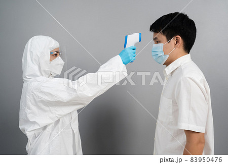 doctor in protective PPE suit using infrared thermometer measuring temperature with people doctor in protective PPE suit using infrared thermometer measuring temperature with people 83950476