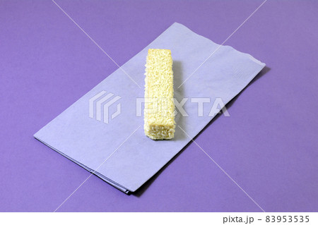 White chocolate and coconut wafer cookie on lavender napkin on purple background White chocolate and coconut wafer cookie on lavender napkin on purple background 83953535