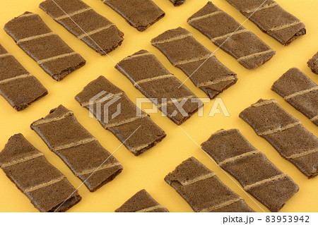 Banana and cocoa chocolate wafer roll snacks on yellow background Banana and cocoa chocolate wafer roll snacks on yellow background 83953942