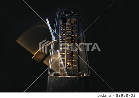 Metronome with moving rod on black background 83958703