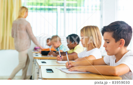 Side view of schoolkids group working on lecture in classroom Side view of schoolkids group working on lecture in classroom 83959030