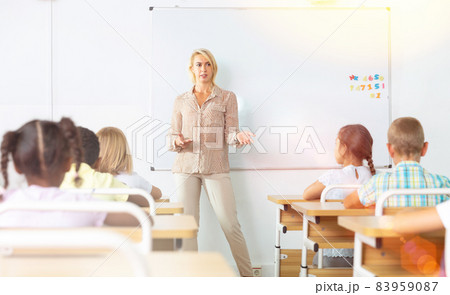 Woman teacher is giving interesting lecture for primary school students in classroom Woman teacher is giving interesting lecture for primary school students in classroom 83959087