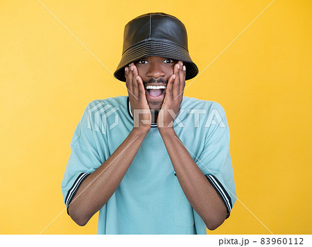Shocked news. Amazed rapper man. Unexpected situation. Surprised happy guy expressing wow reaction hands on cheek isolated yellow. 83960112