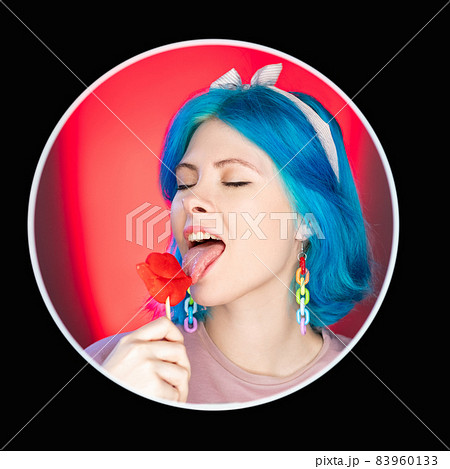 Woman lollipop. Candy lover. Pinup style. Attractive satisfied model licking caramel isolated on red neon light background in round black avatar icon frame. 83960133