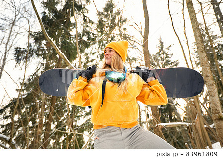 young girl or woman snowboarder goes in for winter sports in snowy forest she stands in snow and holds a snowboard young girl or woman snowboarder goes in for winter sports in snowy forest she stands in snow and holds a snowboard 83961809