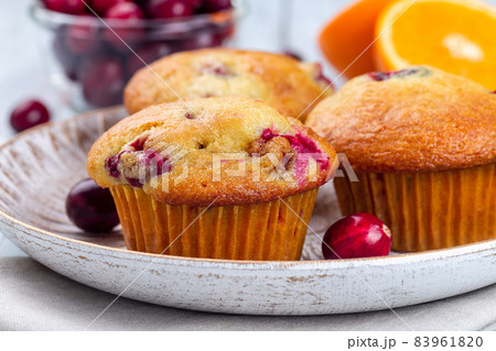 Homemade cranberry orange muffins on wooden plate, horizontal, closeup Homemade cranberry orange muffins on wooden plate, horizontal, closeup 83961820