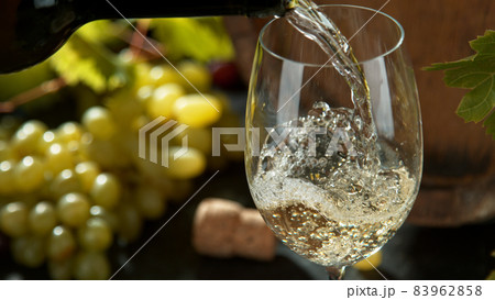 Pouring white wine, black stone background. 83962858
