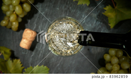 Pouring white wine, black stone background. 83962859