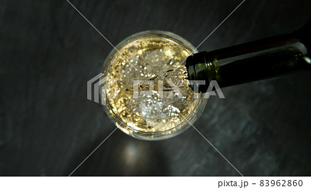 Pouring white wine, black stone background. 83962860