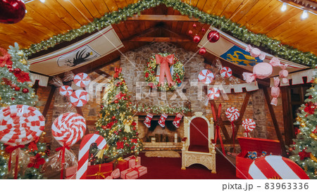 Luxurious red chair Santa Claus throne surrounded by multiple gift boxes. Decorative mailbox Santa Claus workshop, wrapped gifts presents boxes on holiday eve in night on xmas background Luxurious red chair Santa Claus throne surrounded by multiple gift boxes. Decorative mailbox Santa Claus workshop, wrapped gifts presents boxes on holiday eve in night on xmas background 83963336