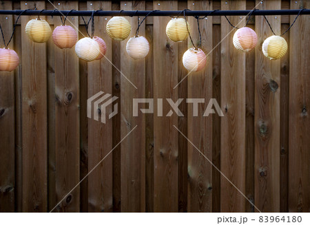 Glowing lanterns lampion lights with delicate design hanging wooden fence,decorative stylish design with copy space. cozy garden decoration 83964180