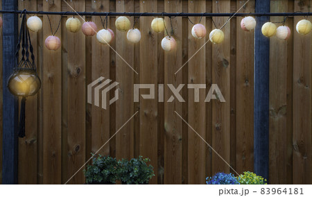 Glowing lanterns lampion lights with delicate design hanging wooden fence,decorative stylish design with copy space. cozy garden decoration 83964181