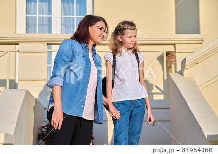 Mother and daughter schoolgirl with a backpack on the porch of the house Mother and daughter schoolgirl with a backpack on the porch of the house 83964360
