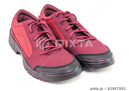 a pair of simple cheap red hiking shoes isolated on white background - perspective close-up view a pair of simple cheap red hiking shoes isolated on white background - perspective close-up view 83967893