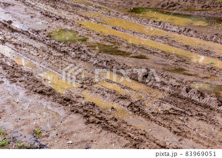 dirty clay mud road with puddles and tire tracks - closeup with selective focus, diagonal composition 83969051