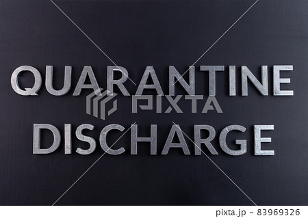 the words quarantine discharge laid with silver metal letters on matte back flat surface directly above in flat lay perspective 83969326