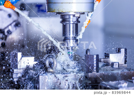 vertical cnc steel milling process with external water coolant streams, splashes and a lot of metal chips, high contrast 83969844