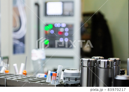 A set of shiny collet chucks in metalworking shop with blurry cnc milling machine inn the background. 83970217